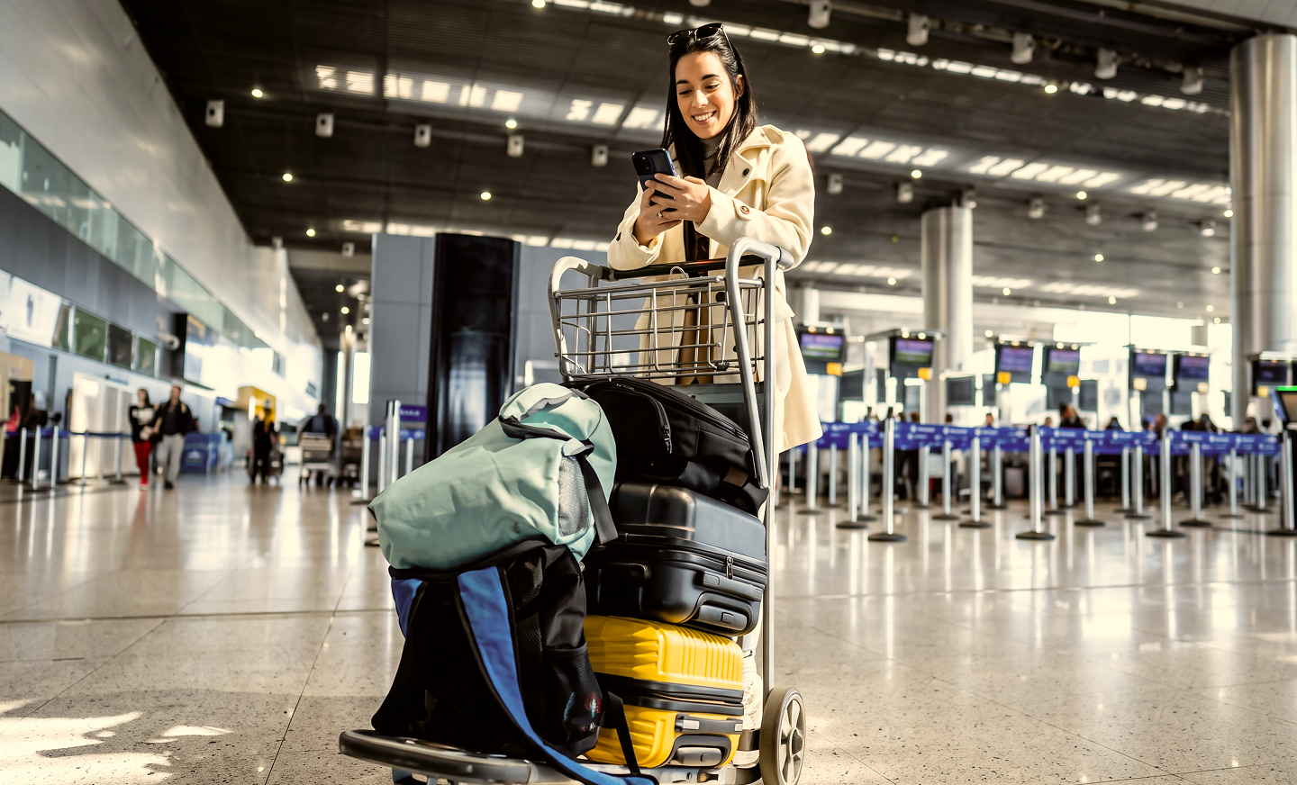 A traveller waiting with a loaded baggage trolley in a departure hall